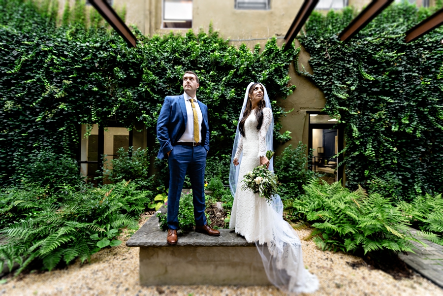 A newly married couple pose in front of an ivy wall in East Falls outside of the Philadelphia Wedding Chapel.